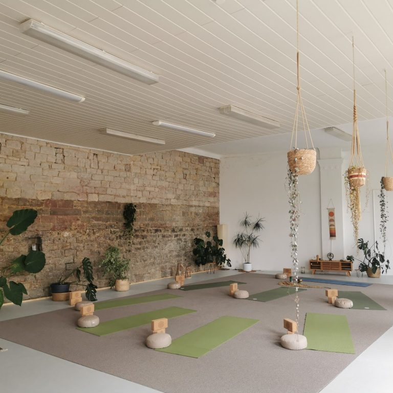 Ein heller Yogaraum mit Matten und Pflanzen.